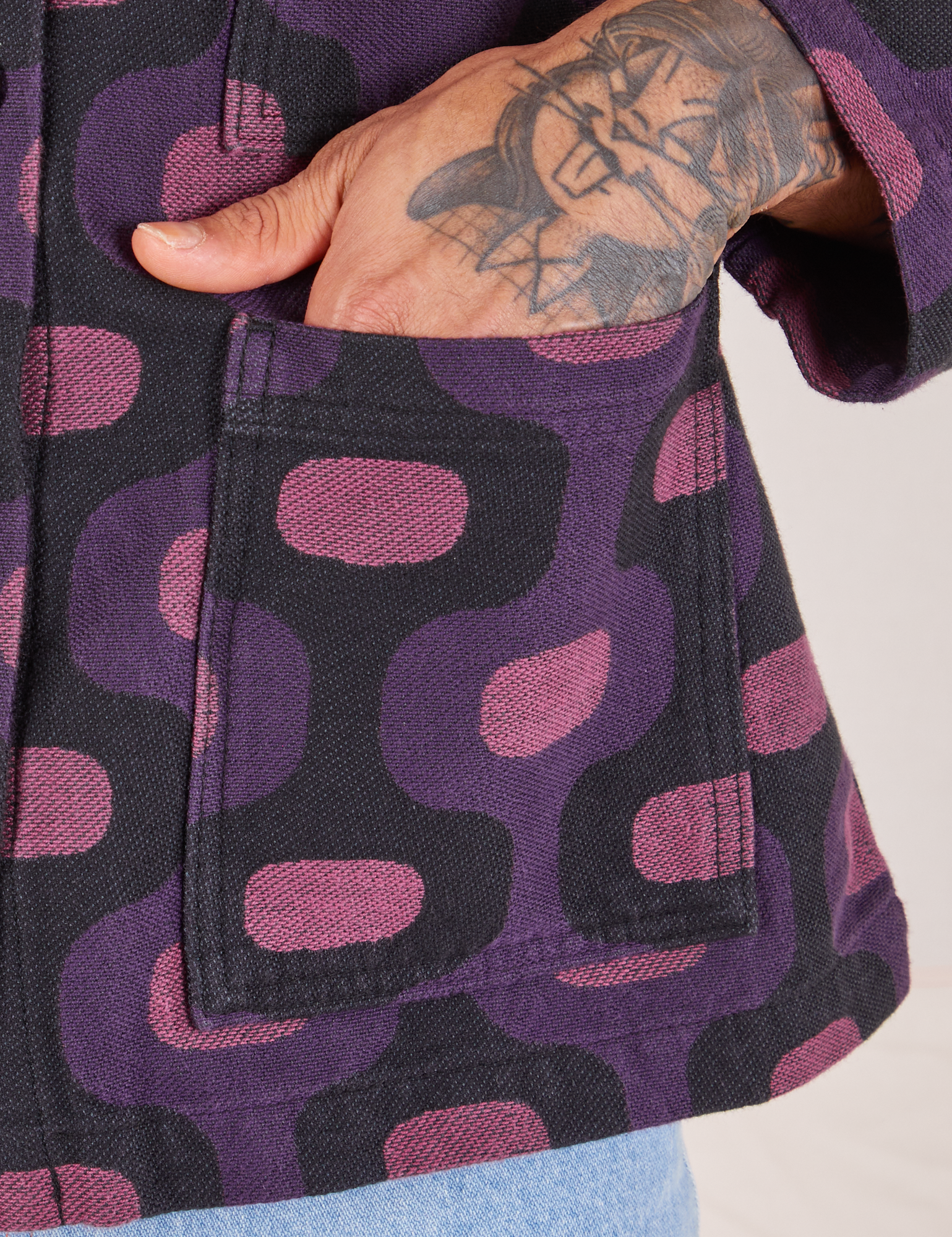  Purple Tile Jacquard Work Jacket front pocket close up. Jesse has their hand in the pocket.