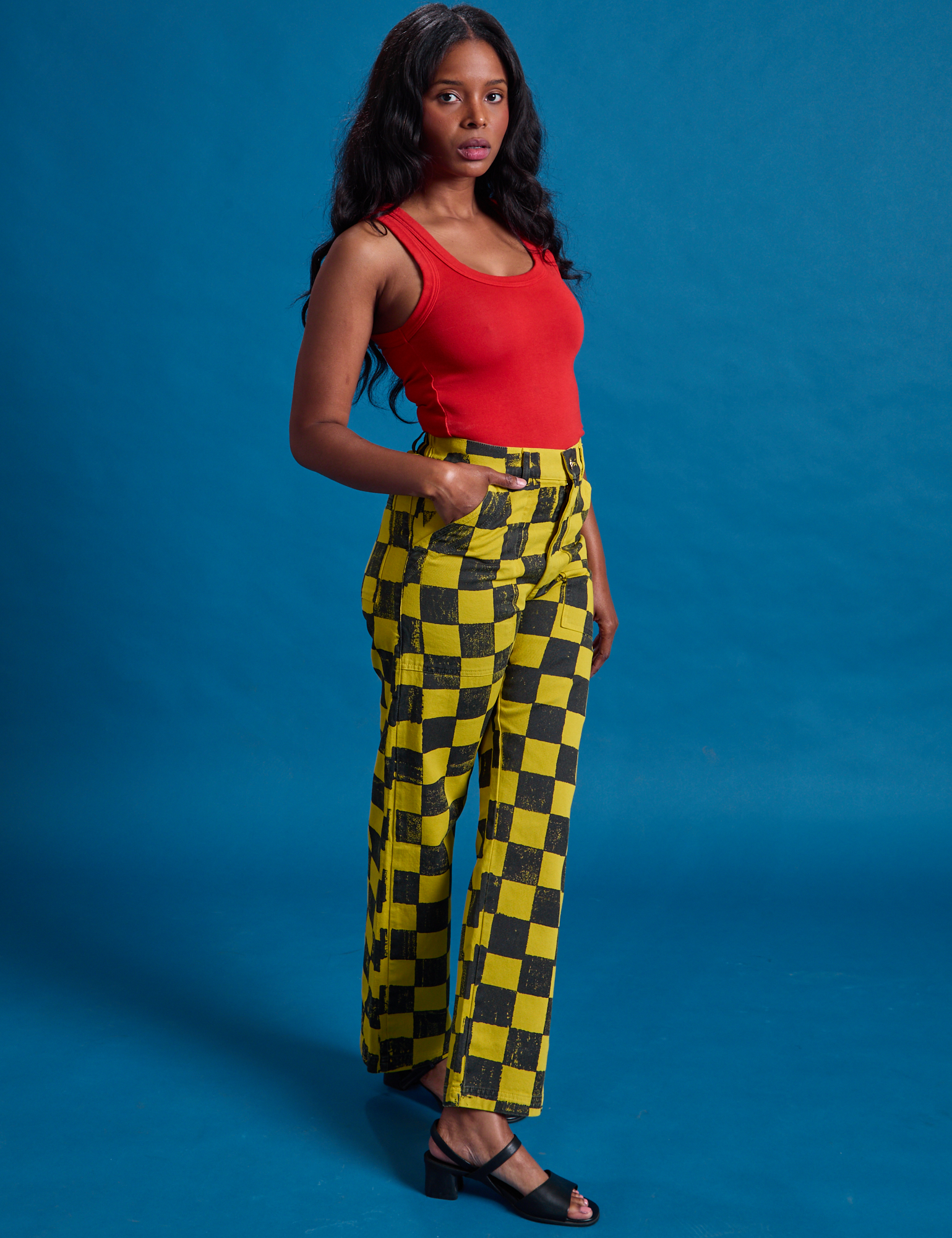 Angled front view of Checkerboard Work Pants in Yellow/Black and mustang red Tank Top on Kandia