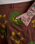Close up of Sam's hand in the back pocket of Floral Painted Work Pants in Brown