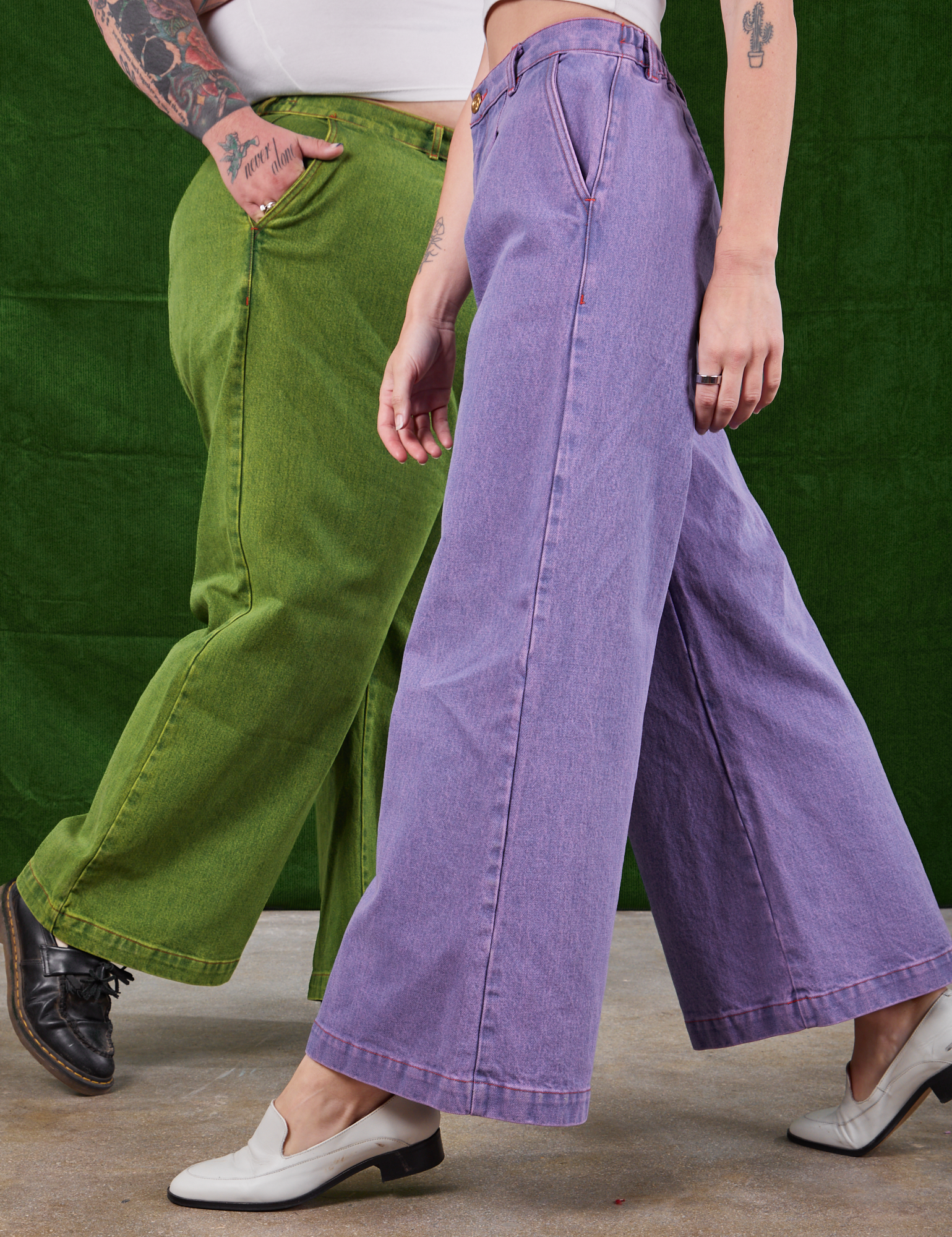 Sam is wearing Overdyed Wide Leg Trousers in Gross Green and Alex is wearing Overdyed Wide Leg Trousers in Faded Grape