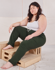 Ashley is wearing Rolled Cuff Sweat Pants in Swamp Green and Cropped Tank in vintage tee off-white. She is sitting on a wooden crate.