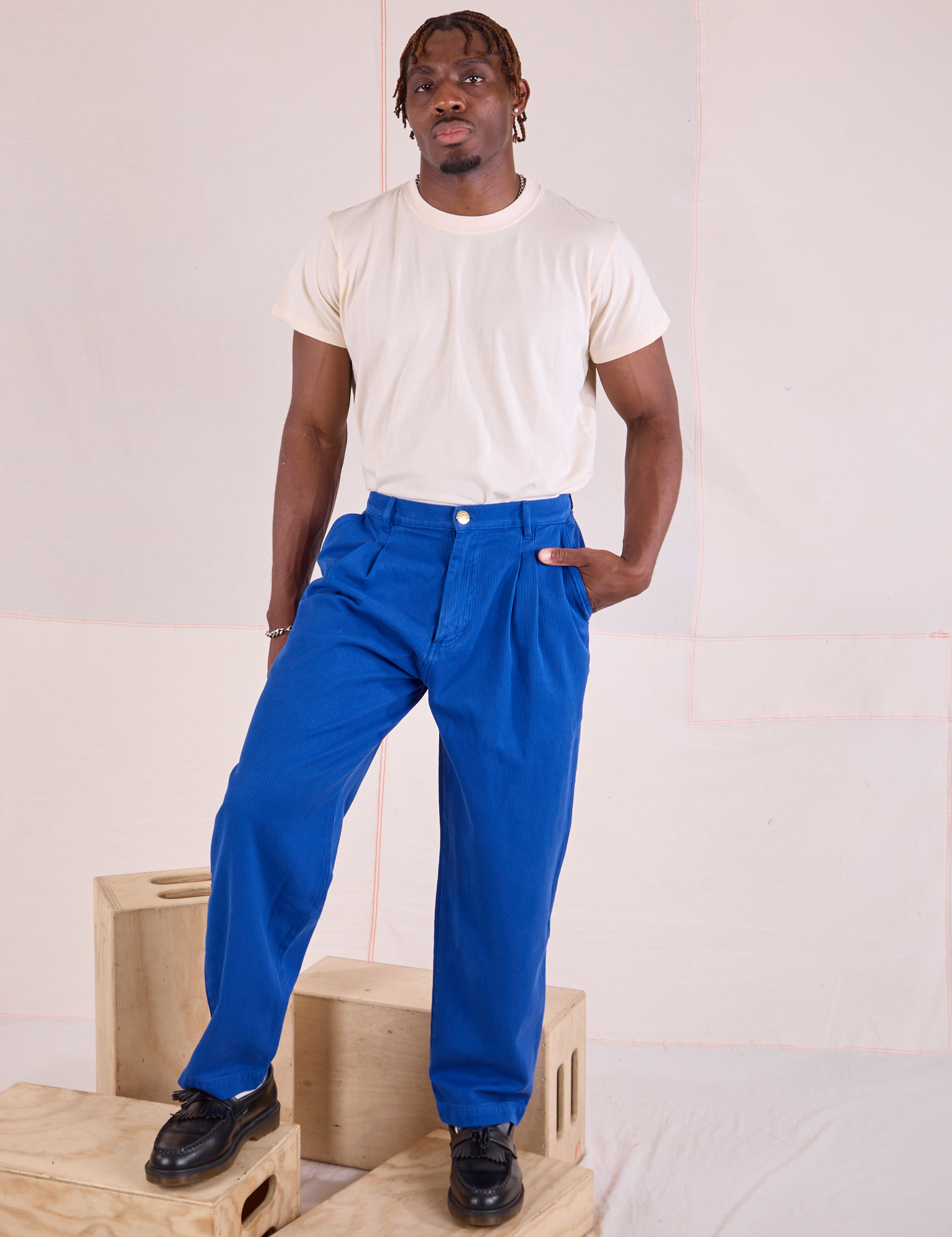 Issac is wearing Heritage Trousers in Royal Blue and tucked in Organic Vintage Tee in vintage tee off-white