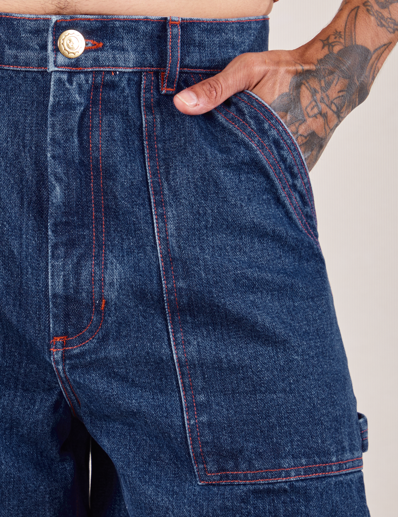 Carpenter Shorts in Dark Wash front pocket close up. Jesse has their hand in the pocket.
