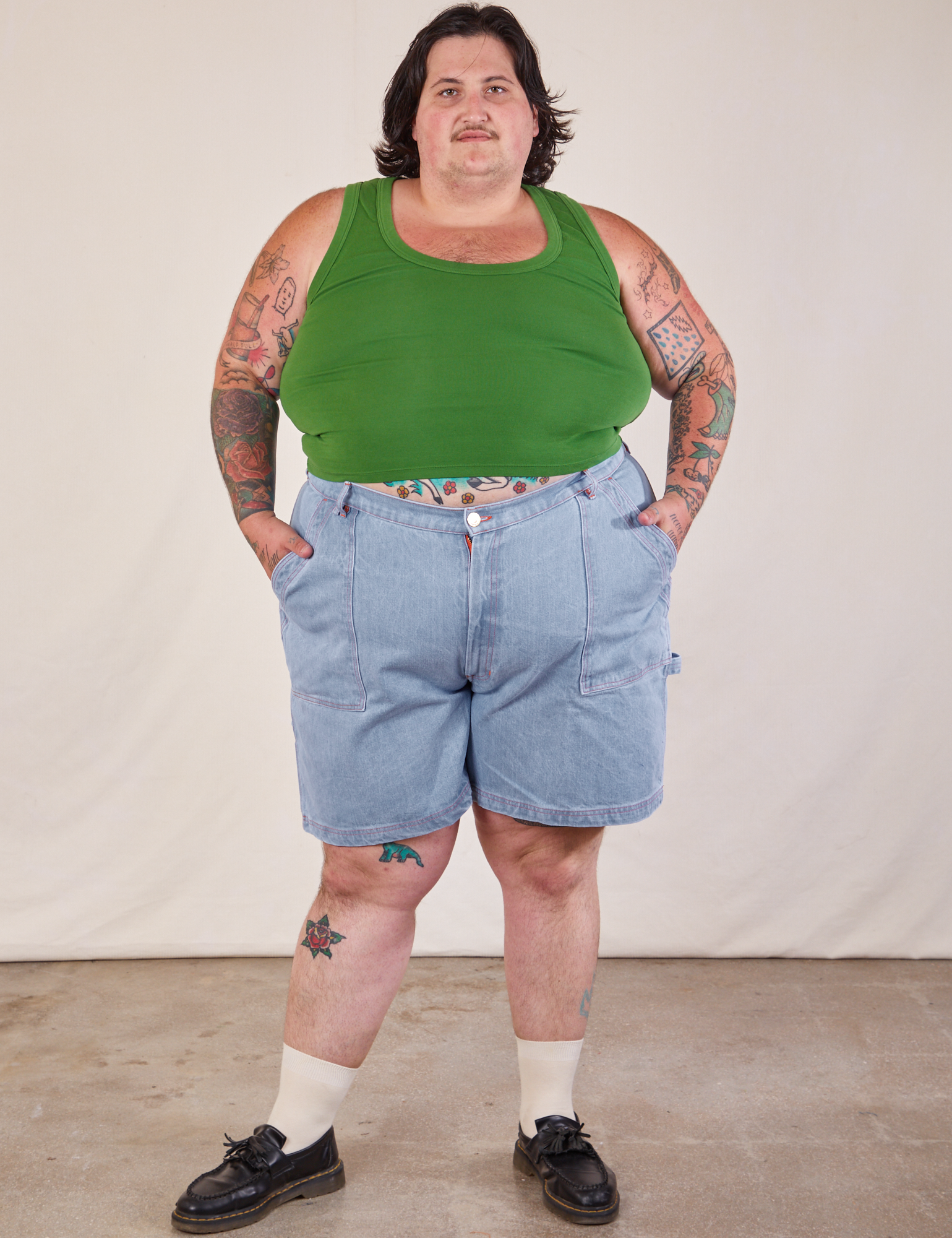 Sam is 5'10" and wearing 3XL Carpenter Shorts in Light Wash paired with a lawn green Cropped Tank