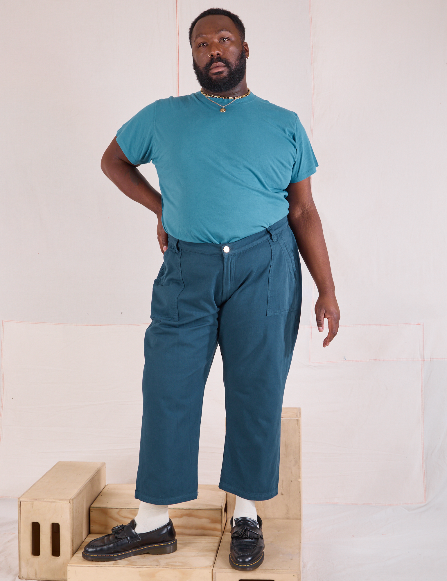Elijah is 6'3" and wearing 1XL Mid-Rise Work Pants in Lagoon paired with marine blue Organic Vintage Tee