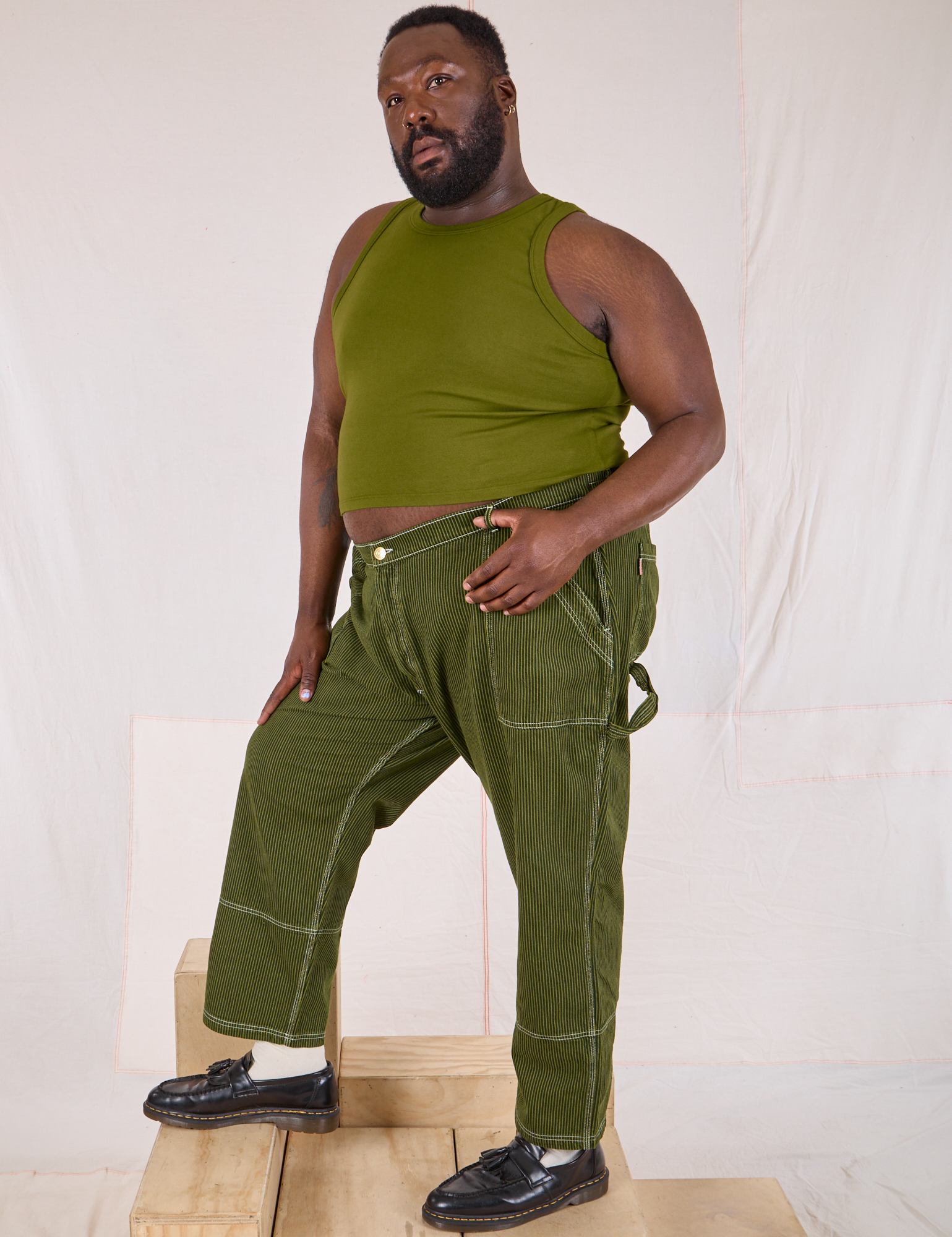 Angled front view of Railroad Carpenter Jeans in Summer Olive
and Muscle Tee on Elijah