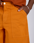 Close up of Isaac's hand in the front pocket of Longline Work Shorts in Creamsicle Orange