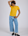 Kira is wearing Jr. Varsity Tee in Sunshine Yellow and light wash Denim Drop Pocket Pants