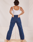 Back view of Carpenter Jeans in Dark Wash and Cropped Cami in vintage tee off-white Tiara has both hands in the back pocket.