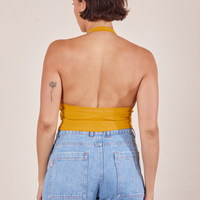 Back view of Halter Top in Mustard Yellow and light wash Sailor Jeans worn by Tiara.
