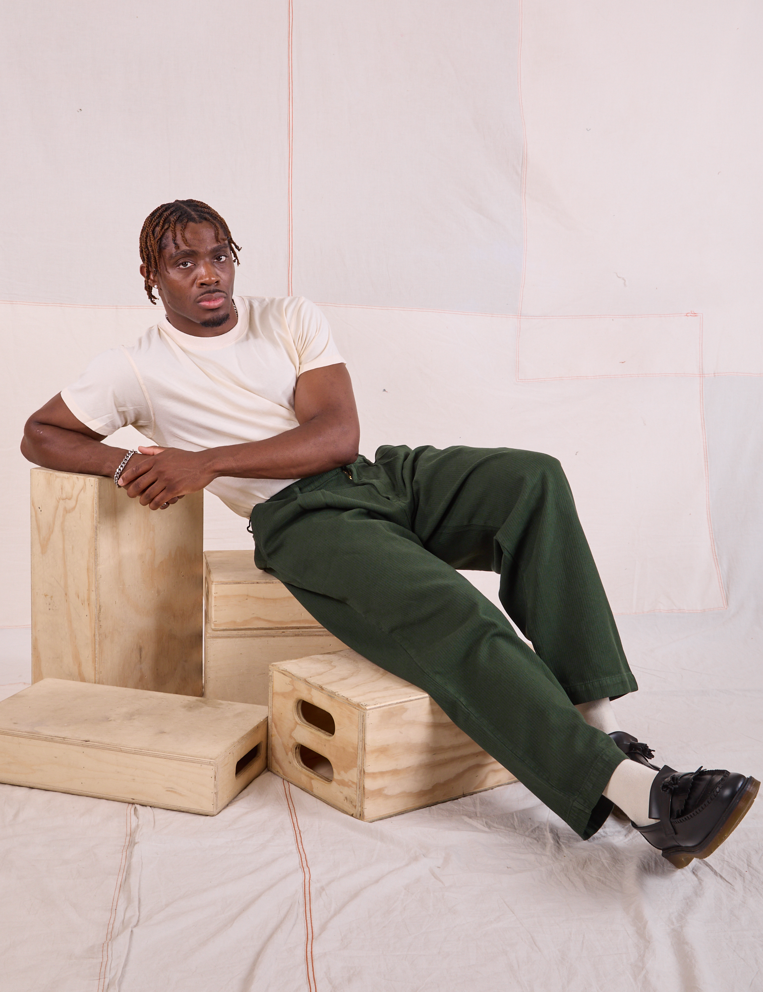 Issac is wearing Heritage Trousers in Swamp Green and Organic Vintage Tee in vintage tee off-white