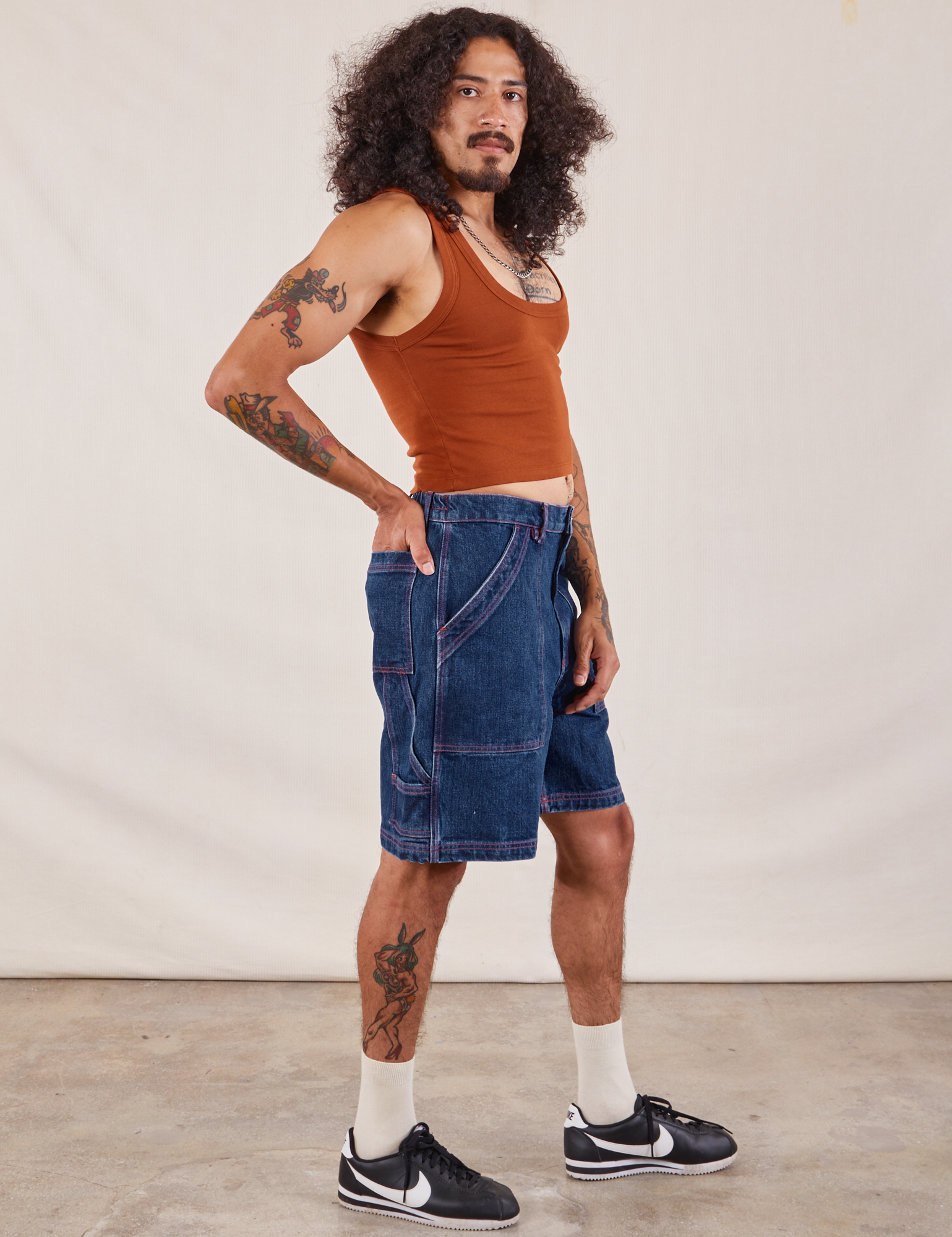 Side view of Carpenter Shorts in Dark Wash and burnt terracotta Cropped Tank on Jesse