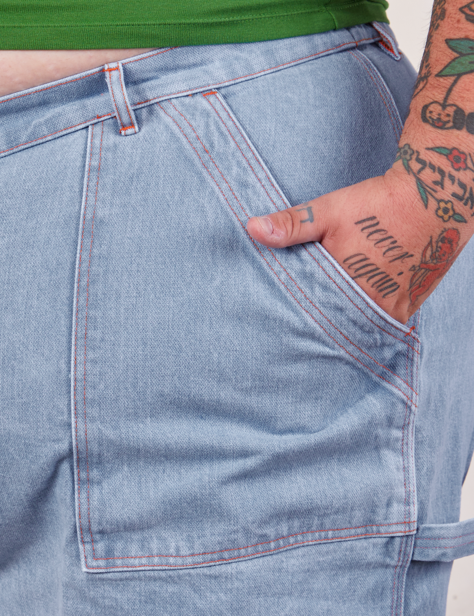 Carpenter Shorts in Light Wash front pocket close up. Sam has their hand in the pocket.