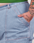 Carpenter Shorts in Light Wash front pocket close up. Sam has their hand in the pocket.