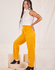 Side view of Organic Trousers in Mustard Yellow and Sleeveless Turtleneck in vintage in off-white worn by Gabi