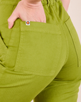 Short Sleeve Jumpsuit in Gross Green back pocket close up. Alex has her hand in the pocket.