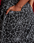 Close up of Kandia's hand in the back pocket of Drop Pocket Cargo Pants in Spider Webs