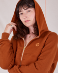 Alex is wearing Cropped Zip Hoodie in Burnt Terracotta with the hood up