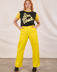 Tiara is wearing Anniversary Tee in I’m Tired tucked into golden yellow Work Pants