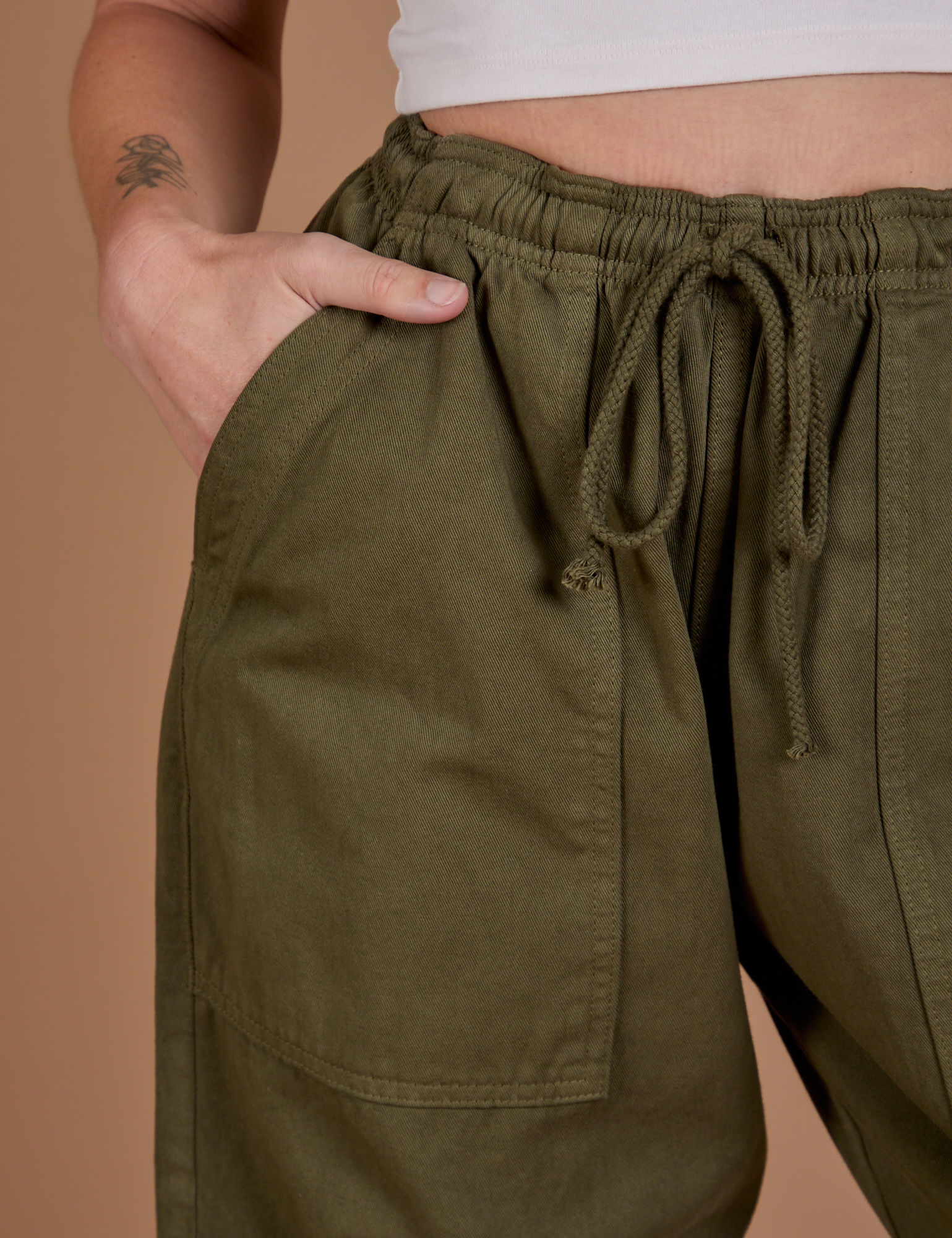 Close up of Alex's hand in the front pocket of Drop Pocket Cargo Pants in Surplus Green