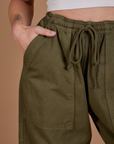 Close up of Alex's hand in the front pocket of Drop Pocket Cargo Pants in Surplus Green