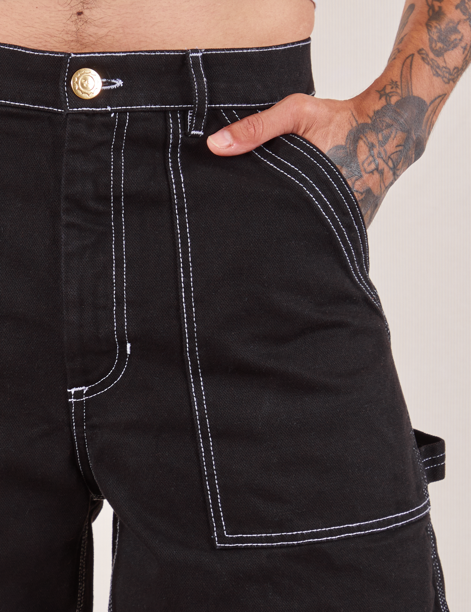 Carpenter Shorts in Basic Black front pocket close up. Jesse has their hand in the pocket.