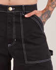 Carpenter Shorts in Basic Black front pocket close up. Jesse has their hand in the pocket.