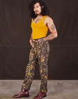 Angled front view of Marble Splatter Work Pants in Espresso Brown and mustard yellow Tank Top on Jesse