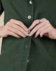 Alex is buttoning up the Pantry Button-Up in Swamp Green