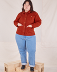 Ashley is wearing Denim Work Jacket in Paprika and light wash Frontier Jeans. She has both hands in the jacket pocket.