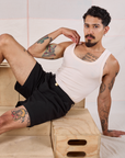 Jesse is wearing a Tank Top in vintage tee off-white and Trouser Shorts in Basic Black