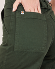 Classic Work Shorts in Swamp Green back pocket close up. Madeline has her hand in the pocket.