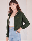 Angled front view of Cropped Zip Hoodie in Swamp Green, vintage off-white Cropped Tank and light wash Carpenter Jeans