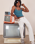 Three vintage tvs are stacked on top of each other. Jerrod is sitting on the large tv with his right elbow on a smaller orange and white tv. They are wearing Cropped Cami in Marine Blue and vintage tee off-white Western Pants.