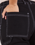 Carpenter Jeans in Black back pocket close up. Tiara has her hand tucked into the pocket.