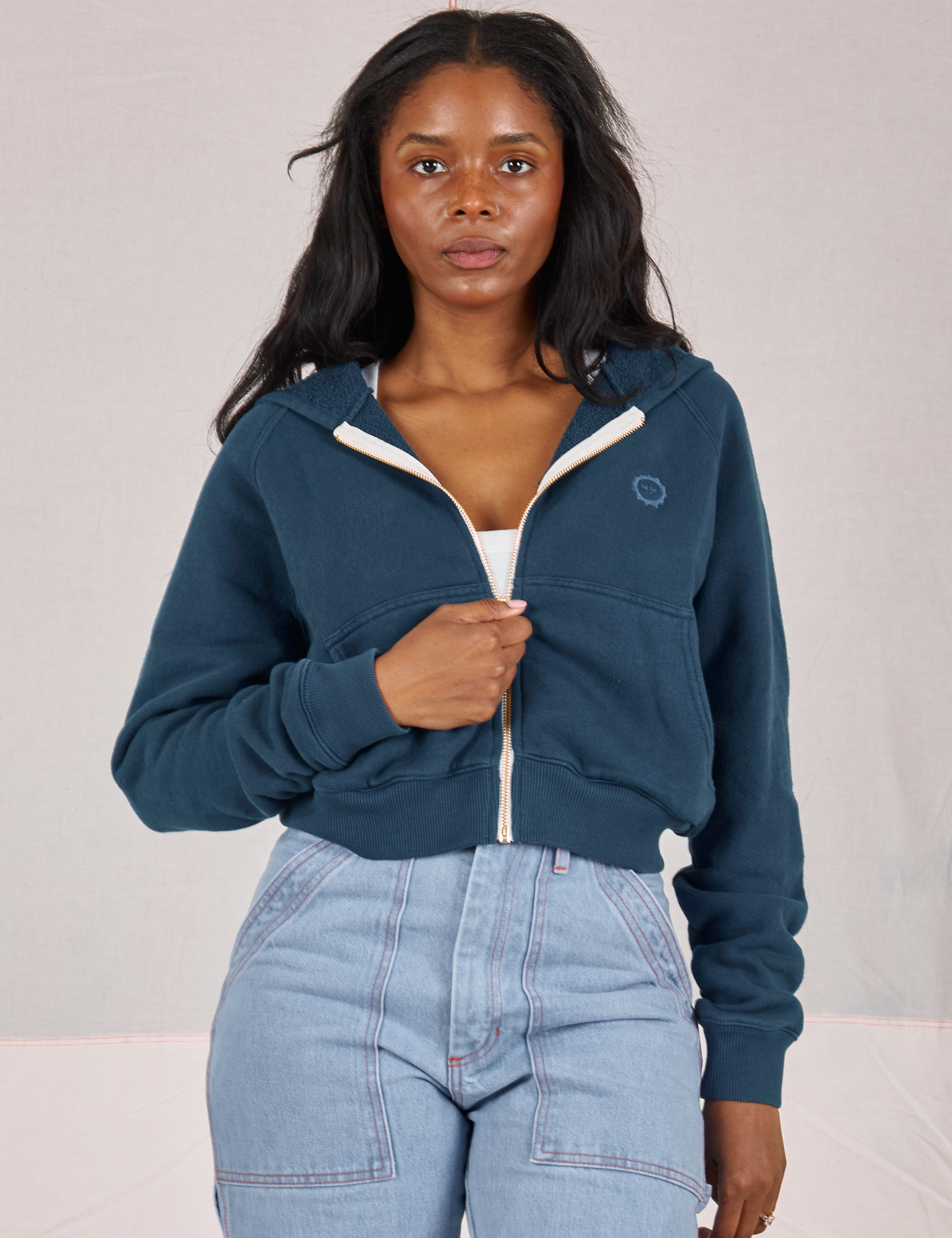 Kandia is wearing Cropped Zip Hoodie in Lagoon and light wash Carpenter Jeans