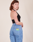 Angled back view of Halter Top in Basic Black and light wash Frontier Jeans worn by Alex