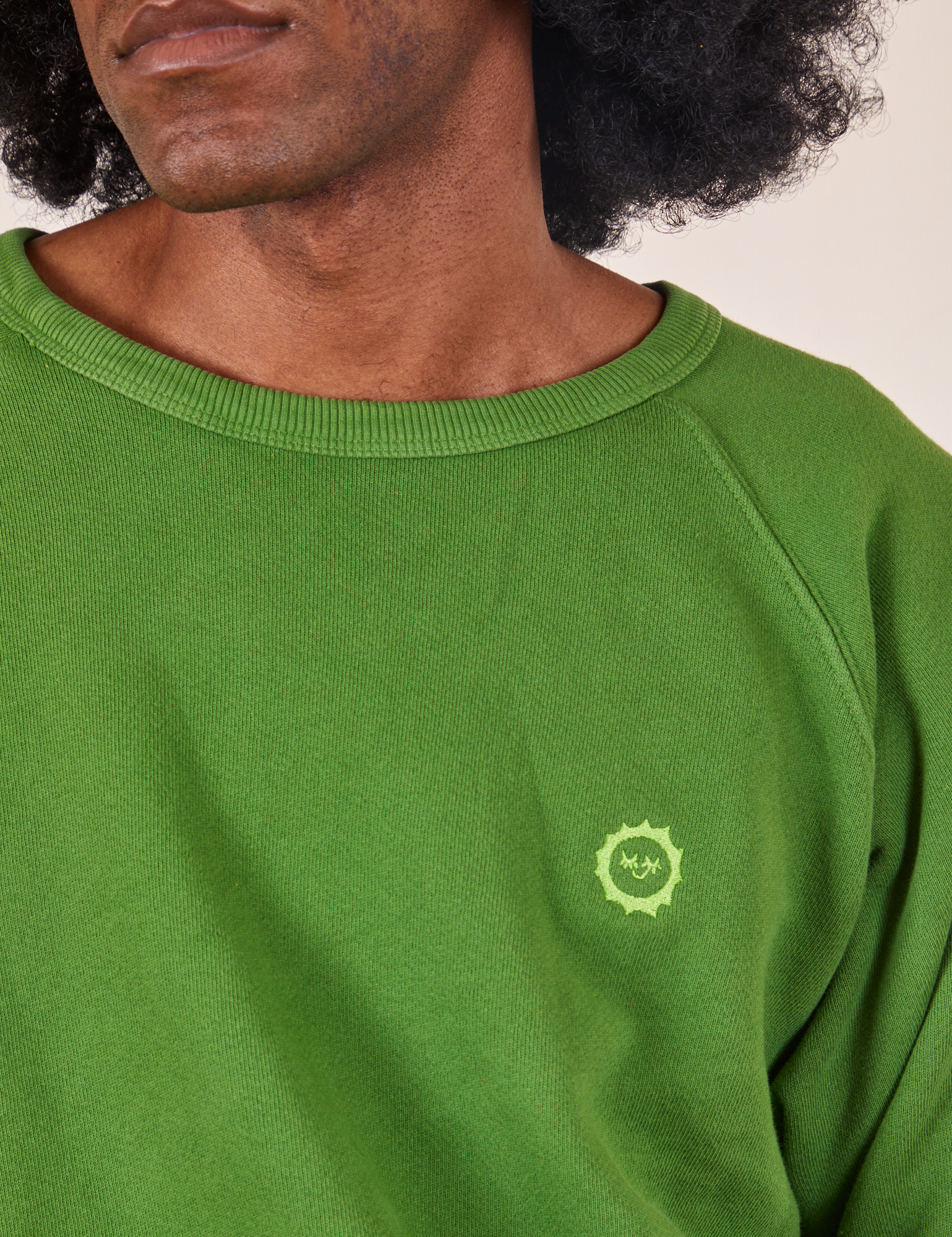 Heavyweight Crew in Lawn Green front close up on Jerrod. Embroidered Sun Baby Logo.