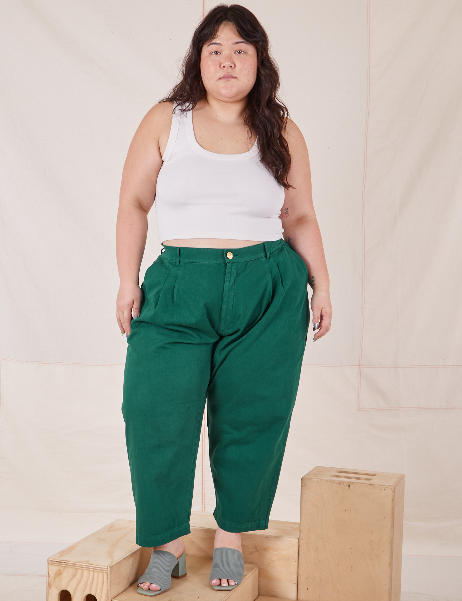 Ashley is 5&#39;7&quot; and wearing 1XL Petite Heavyweight Trousers in Hunter Green paired with Cropped Tank Top in vintage tee off-white