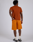 Back view of Longline Work Shorts in Creamsicle Orange and burnt terracotta Organic Vintage Tee on Isaac