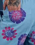 Close up of Jesse's hand in the back pocket of Floral Painted Work Pants in Blue