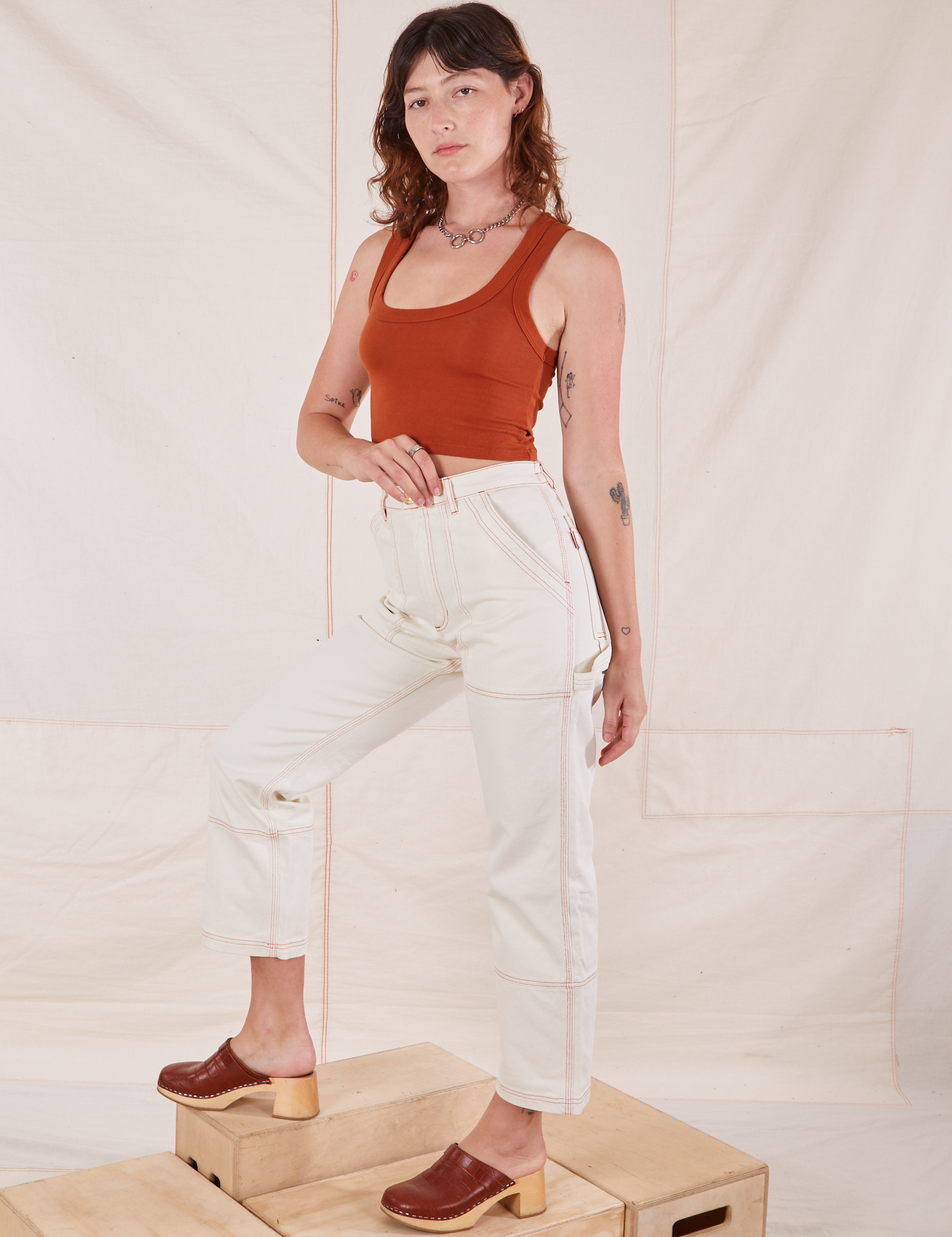 Alex is wearing Carpenter Jeans in Vintage Tee Off-White and burnt terracotta Cropped Tank Top