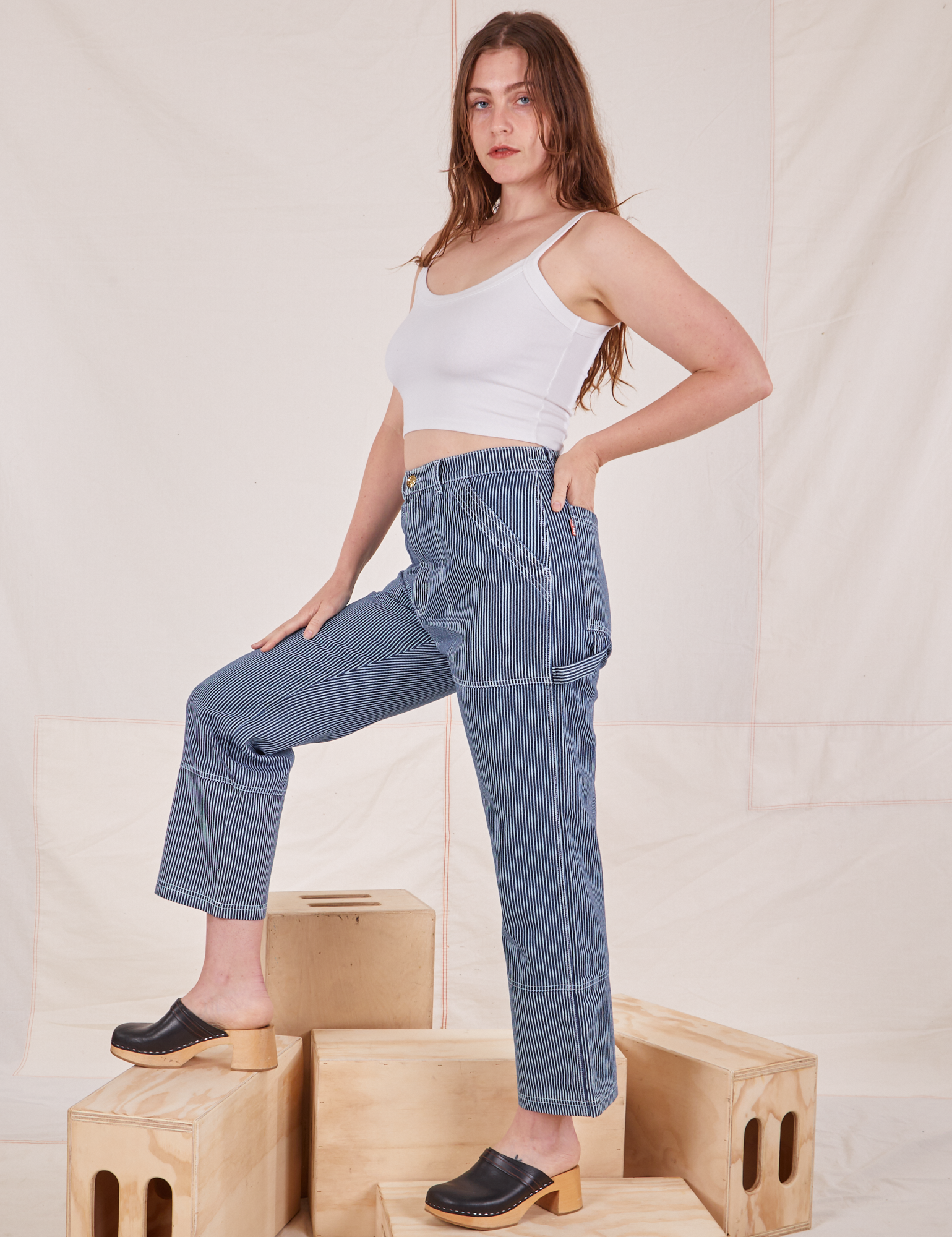 Side view of Carpenter Jeans in Railroad Stripes and Cropped Cami in vintage tee off-white worn by Allison