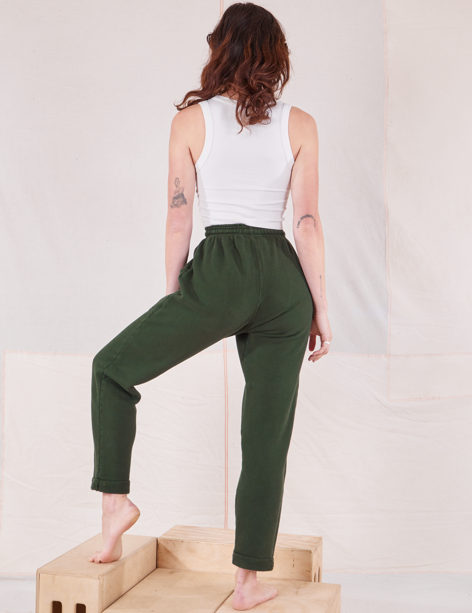 Back view of Rolled Cuff Sweat Pants in Swamp Green and Cropped Tank in vintage tee off-white on Alex