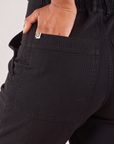 Heritage Short Sleeve Jumpsuit in Basic Black back pocket close up. Mika has her hand in the pocket.