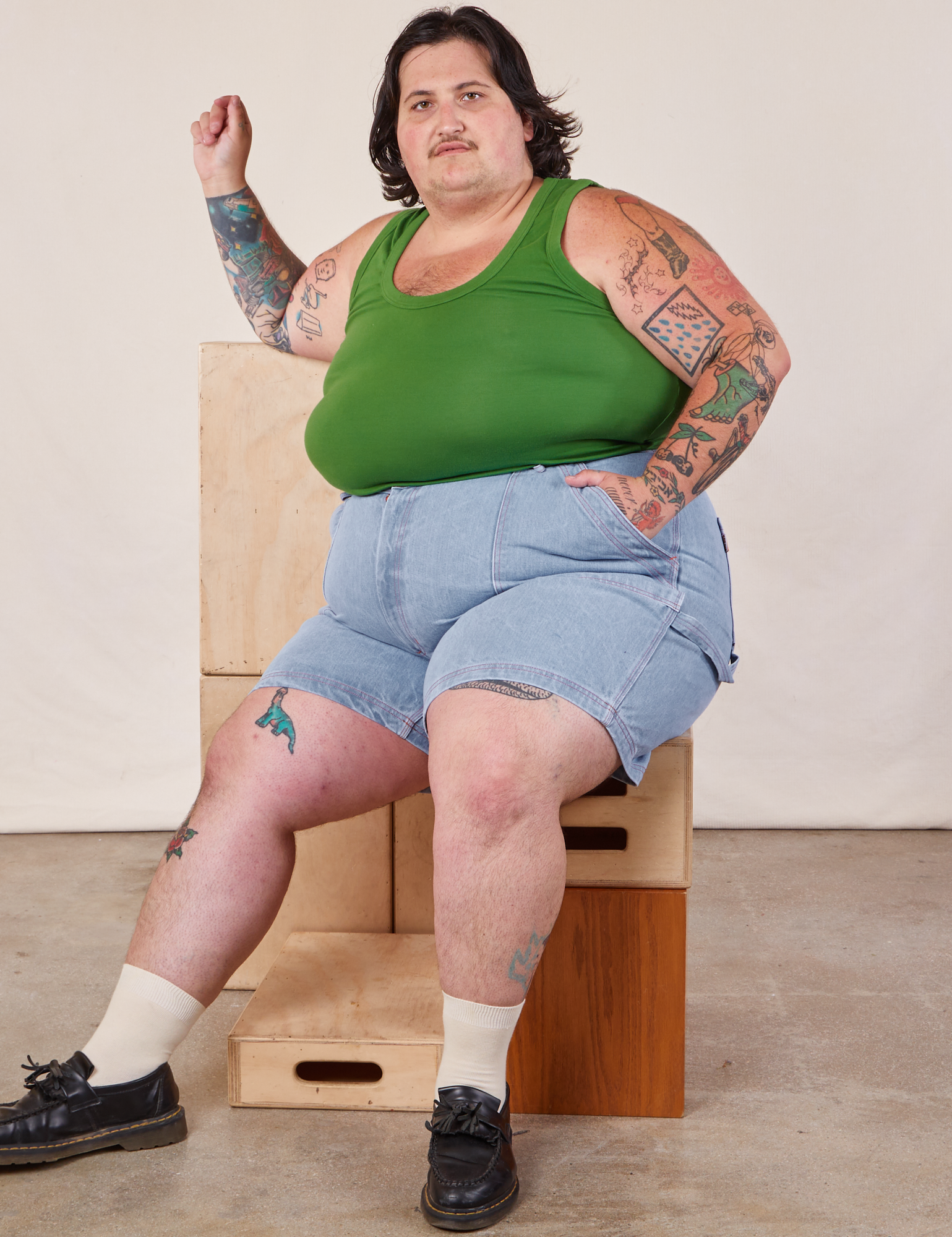 Sam is wearing Carpenter Shorts in Light Wash and lawn green Cropped Tank