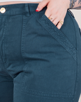 Work Pants in Lagoon front pocket close up. Sydney has her hand in the pocket.