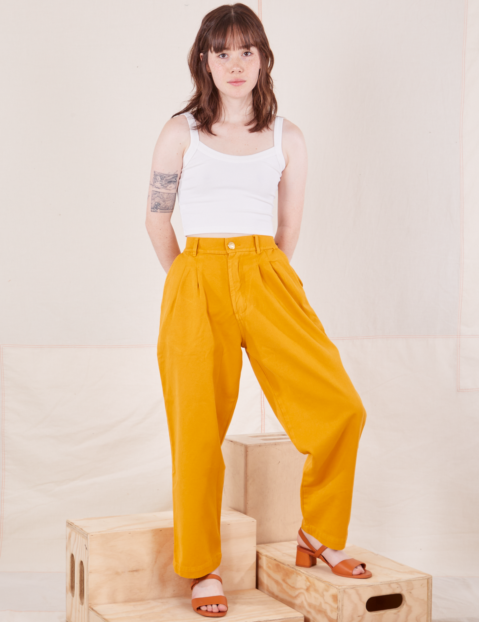 Hana is 5&#39;3&quot; and wearing XXS Petite Organic Trousers in Mustard Yellow paired with Cropped Cami in vintage tee off-white