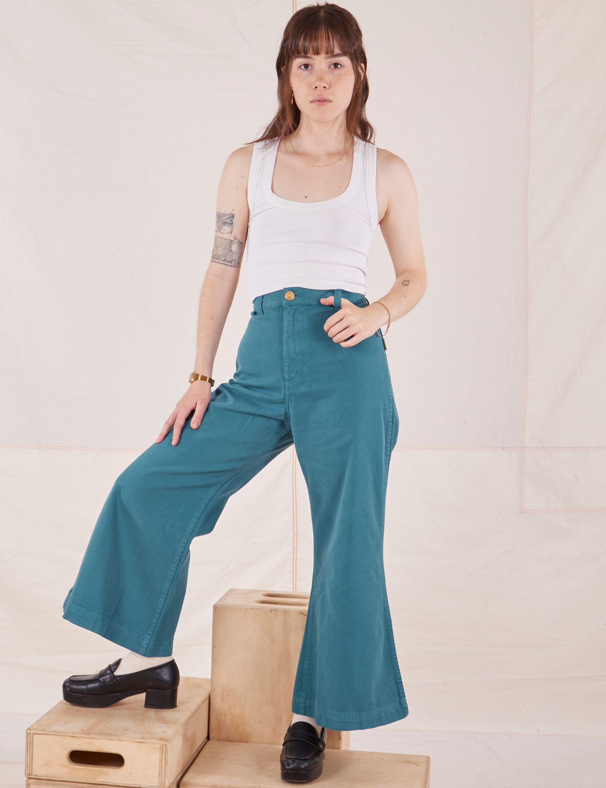 Hana is 5&#39;3&quot; and wearing P Petite Bell Bottoms in Marine Blue paired with Cropped Tank Top in vintage tee off-white