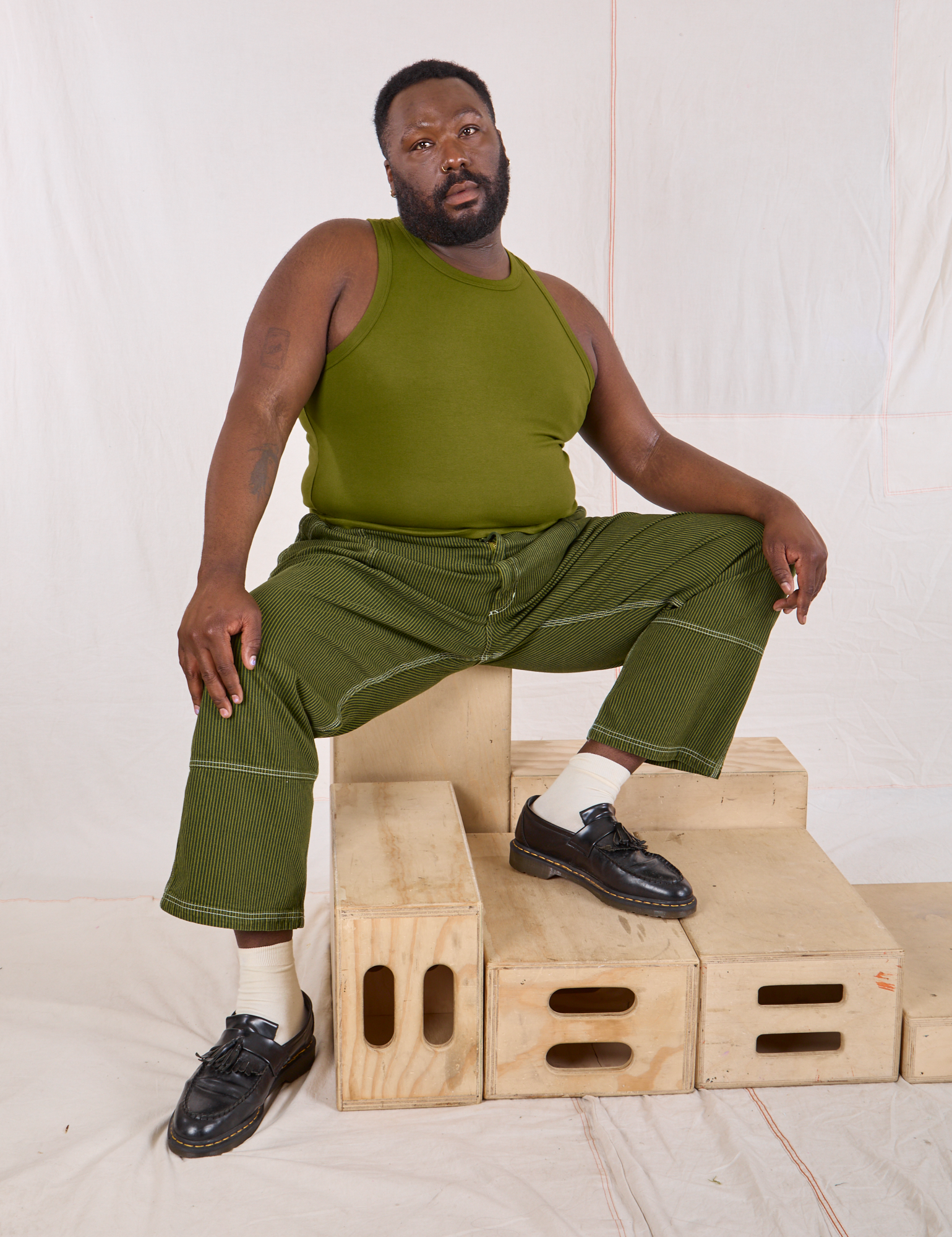 Elijah is wearing Railroad Carpenter Jeans in Summer Olive and summer olive Muscle Tee